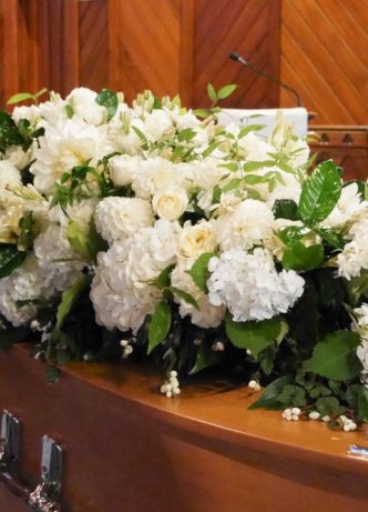 Casket With Flowers On Top — Newhaven Funerals in Logan, QLD