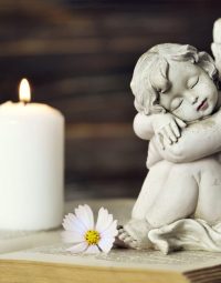 White Candle, Flowers and Statue — Newhaven Funerals in Brisbane
