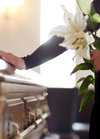 Woman Holding White Lillies At Funeral —