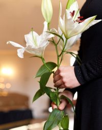 Woman In Black Holding Flowers — Newhaven Funerals in Brisbane