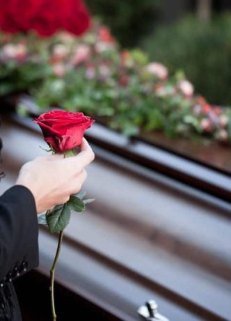 Woman Holding Rose Next To Coffin — Newhaven Funerals in Brisbane